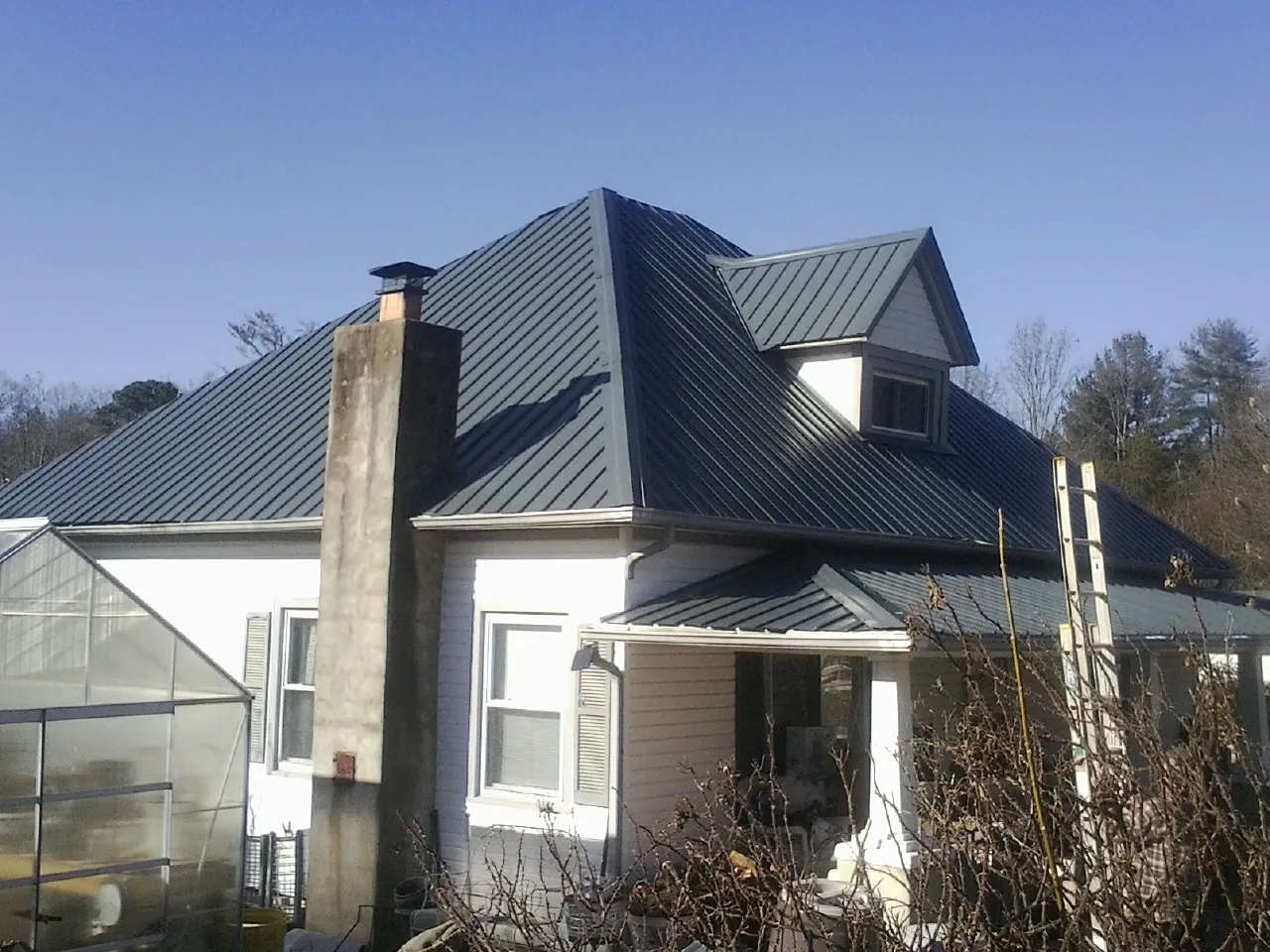 Dark blue standing seam metal roof on a white farmhouse with dormer — Slate & Tile Roof Repair by Roofing Brothers in Frankfort