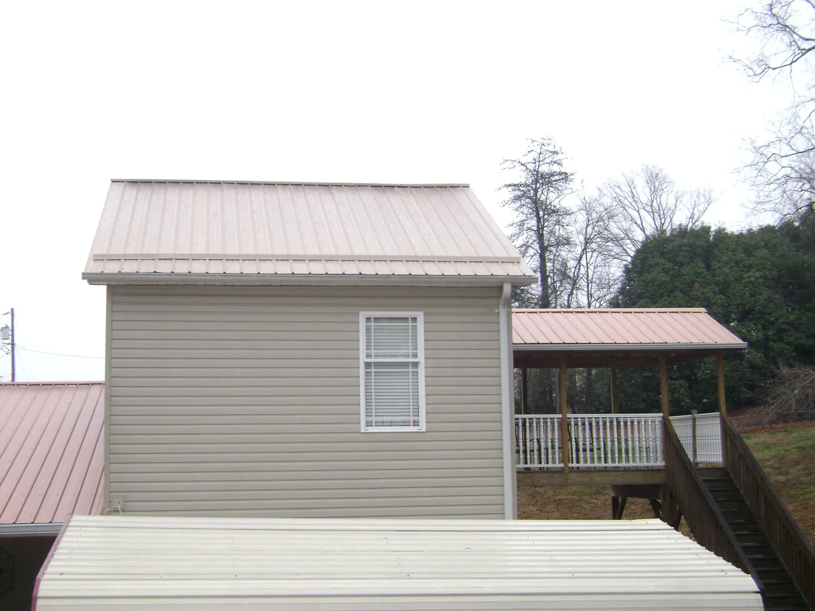 Tan metal roofs on a two story addition and attached porch, from a Roof Replacement job in Frankfort
